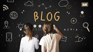 blog1 - KiddieCove - KiddieCove Two people seen from behind stand at a chalkboard wall covered with blog-themed doodles and the word BLOG in orange.